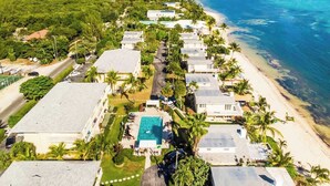 Ett flygbildsbild av en kustort med flera byggnader, en swimmingpool och en strand.