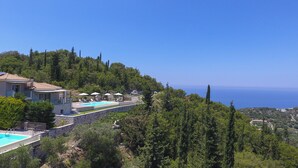 A hillside villa with a swimming pool, stone walls, and a view of the sea. - Drimonari Villas (Lefkada)