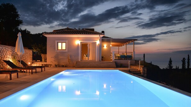 A modern house with a swimming pool, stone wall, and outdoor seating area. - Drimonari Villas (Lefkada)
