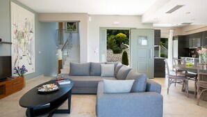 A modern living room with a sectional sofa, a coffee table, and a dining area with a table and chairs. - Drimonari Villas (Lefkada)