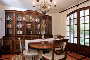 A dining room with a wooden table, chairs, a cabinet with glass doors, and a chandelier.