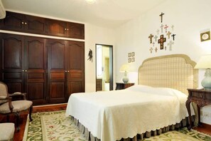 A bedroom with a large bed, wooden wardrobe, and a wall with religious symbols.