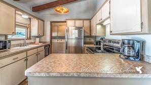 A kitchen with a large island, stainless steel appliances, and wooden beams on the ceiling. - Bluebird View | Sierra Blanca Views + Hot Tub Retreat (Ruidoso)
