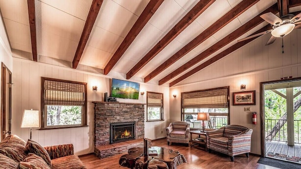 A cozy cabin interior with a fireplace, wooden beams, and comfortable seating. - Bluebird View | Sierra Blanca Views + Hot Tub Retreat (Ruidoso)