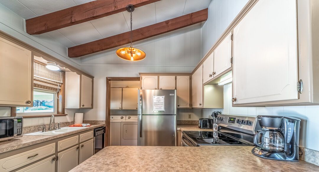 A kitchen with a large island, stainless steel appliances, and wooden beams on the ceiling.