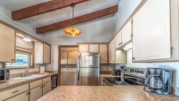 A kitchen with a large island, stainless steel appliances, and wooden beams on the ceiling.