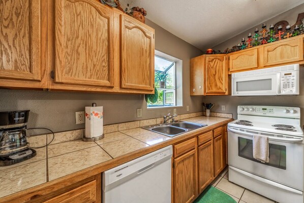 A kitchen with wooden cabinets, a white microwave, a stove, and a dishwasher.