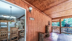 Un intérieur en bois comprenant un coin repas, un banc en pierre et une vue sur la verdure environnante.