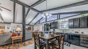Una cocina amplia con techos altos, ventanas grandes y un comedor con muebles de madera.