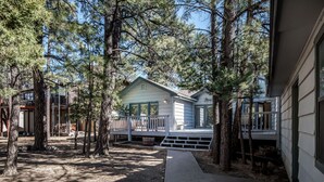 A house with a porch, surrounded by tall trees. - Angulo | Your Perfect Angle on Relaxation w/ Hot Tub & Deck (Alto)