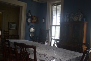 Un comedor con una mesa de mármol, sillas de madera, un aparador con objetos decorativos y un ventanal grande.