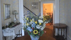 A dining room with a wooden table, a floral centerpiece, and a staircase in the background. - Historic Victorian - 1 Hour N of Nashville (Russellville)
