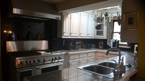 A kitchen with a stainless steel range, double sink, white cabinets, and a window providing natural light. - Historic Victorian - 1 Hour N of Nashville (Russellville)