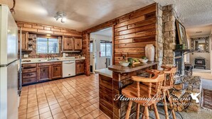 Una cocina rústica con armarios de madera, una pared de acento de piedra y una zona de bar con taburetes.