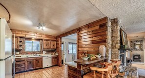 Une cuisine rustique avec des meubles en bois, un mur d’accent en pierre et un coin bar avec des tabourets.