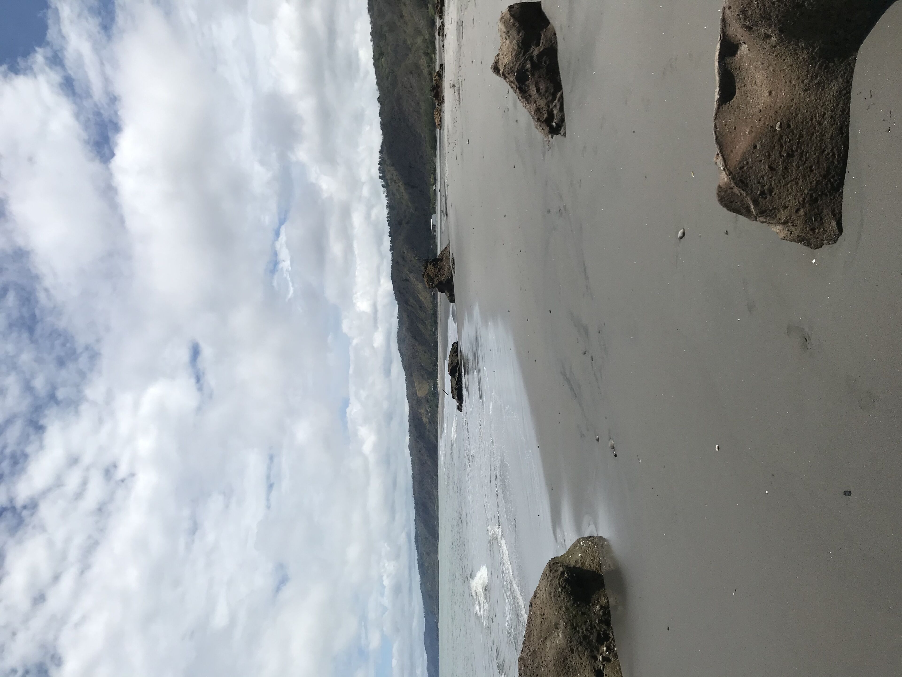 Una playa con rocas grandes y cielo nublado.