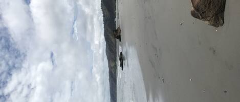 Una playa con rocas grandes y cielo nublado.