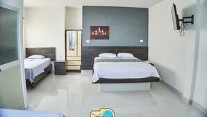 A hotel room with two beds, a wardrobe, a mirror, and a wall-mounted TV. - Hostería Pacific Stone (Tachina)