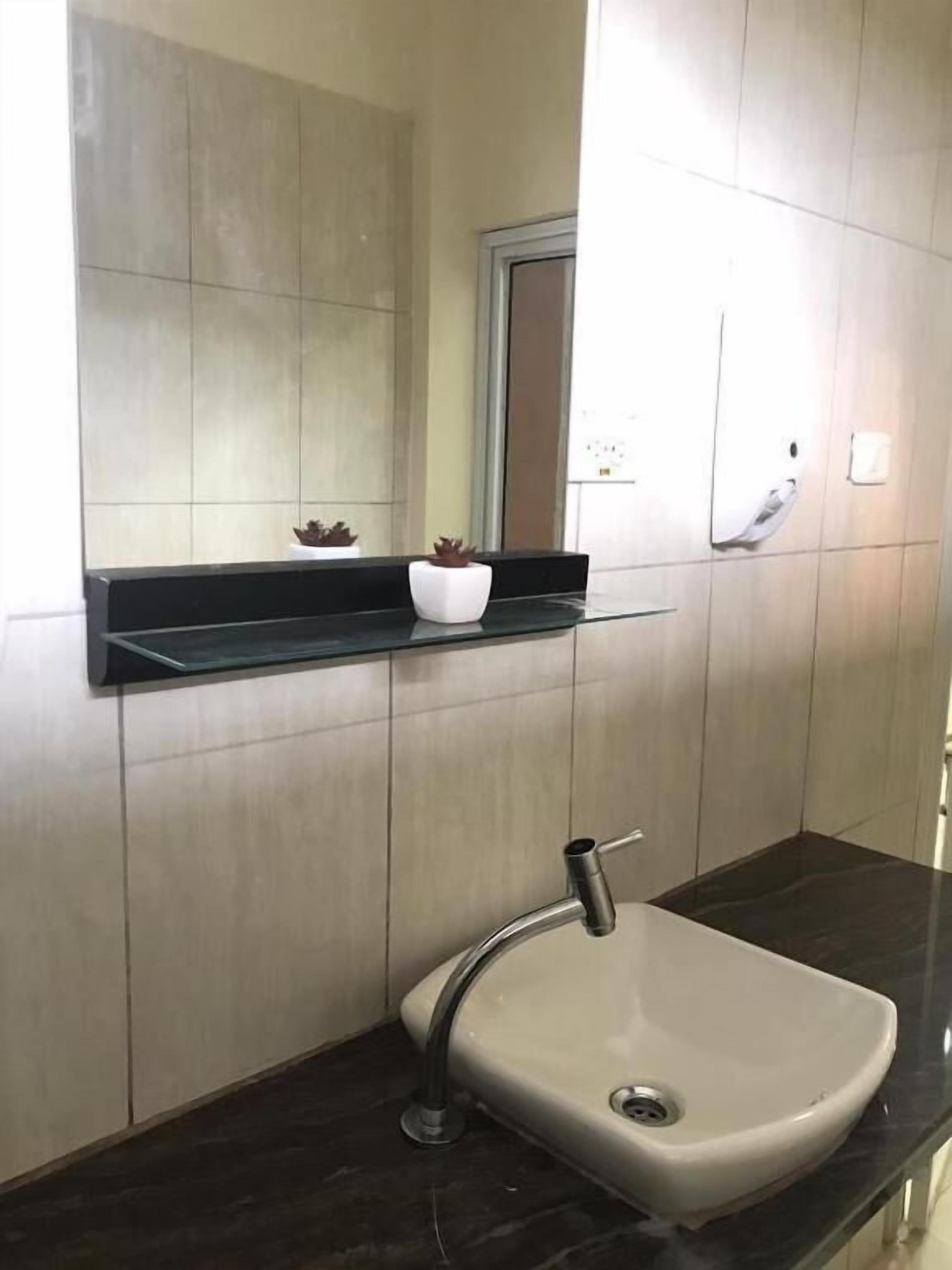 A bathroom with a black countertop, a white sink, and a mirror above it.