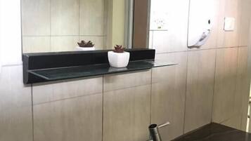 A bathroom with a black countertop, a white sink, and a mirror above it.