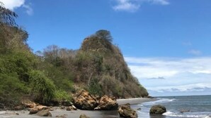 A beach with a rocky shoreline, a sandy beach, and a hill with vegetation. - Hostería Pacific Stone (Tachina)
