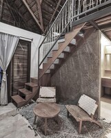 Un interior moderno con una escalera de madera, una mesa redonda de madera y sillas tejidas.