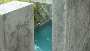 A woman in a black bikini entering a swimming pool through a concrete archway. - Casa Hormiga (Bacalar)