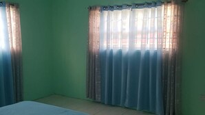Una stanza con un letto, una finestra con tende e una parete verde.