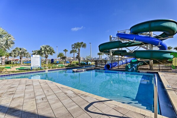 Enjoy a refreshing swim in the pool surrounded by a deck area and palm trees.