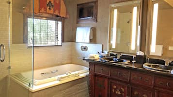 A bathroom with a bathtub, a vanity with a mirror, and a window with blinds.