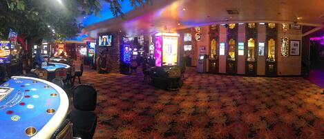 Un espace de casino comprenant des machines à sous, des tables de blackjack et un sol recouvert de moquette.