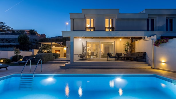 Une maison moderne dotée d’une piscine, d’un espace extérieur aménagé et d’une entrée bien éclairée.