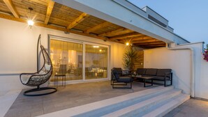 Un patio extérieur abrité, équipé d’une chaise suspendue, d’un canapé et d’une table à manger.