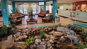A lobby with seating areas, a reception desk, and a small indoor garden with rocks and plants. - Perfect Disney/Golf Vacation Condo (Davenport)