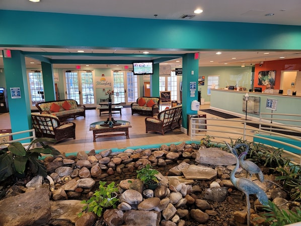 A lobby with seating areas, a reception desk, and a small indoor garden with rocks and plants.