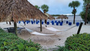 A beach with thatched umbrellas, blue lounge chairs, and a hammock. - Perfect Disney/Golf Vacation Condo (Davenport)