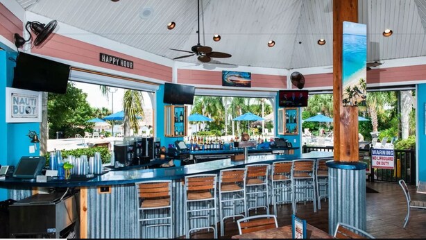 A bar area with a counter, bar stools, and a ceiling fan. - Perfect Disney/Golf Vacation Condo (Davenport)