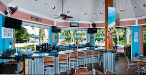 A bar area with a counter, bar stools, and a ceiling fan.