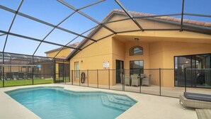 Une piscine intérieure protégée par une paroi de verre, un patio couvert et un espace extérieur aménagé avec des sièges.