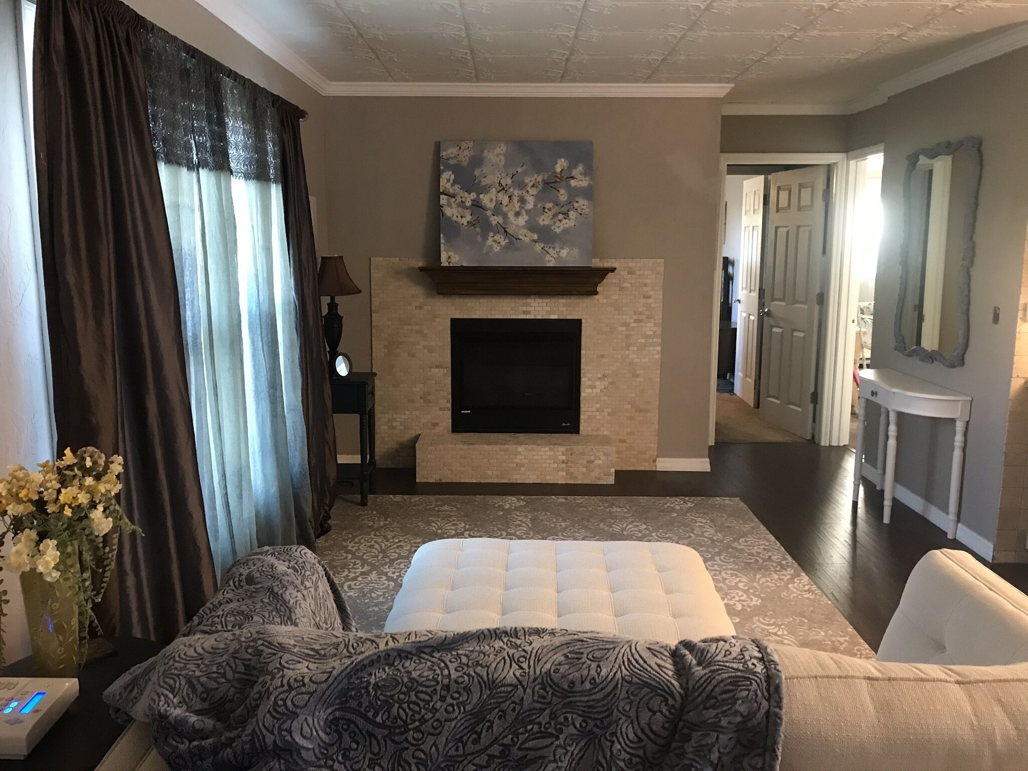 A hotel room with a fireplace, a bed, a sofa, a TV, and a hallway with a mirror.