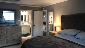 Ein Schlafzimmer mit Bett, Schminktisch, Kommode, Deckenventilator und Fenster.