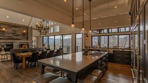 Une cuisine spacieuse dotée d’un grand îlot central, de planchers en bois foncé et d’une cheminée en pierre.