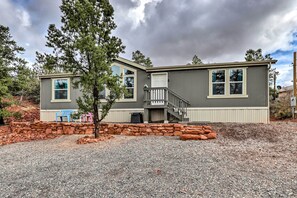 A two-story house with a stone foundation, a front porch, and a staircase leading to the upper level. - Mountain-View Rooftop Deck: Sedona Hideaway (Sedona)