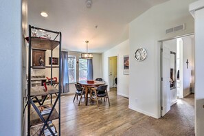 A dining area with a round table and chairs, a chandelier, and a kitchen in the background. - Mountain-View Rooftop Deck: Sedona Hideaway (Sedona)