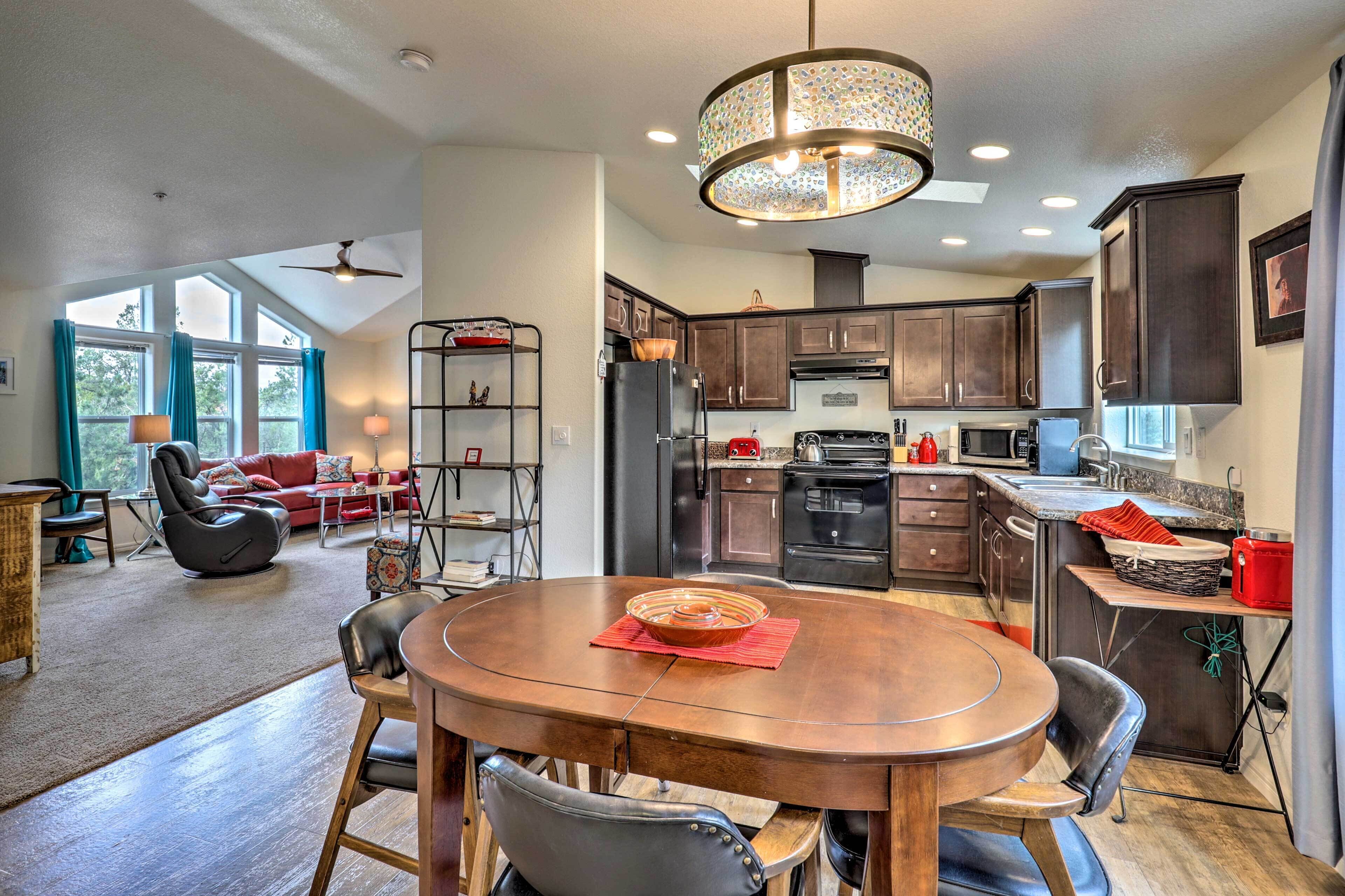 A spacious kitchen with dark wooden cabinets, a central island, and a dining area with a round table and chairs.