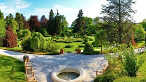 Un jardin agrémenté d’une fontaine circulaire, de bancs et de haies soigneusement taillées.
