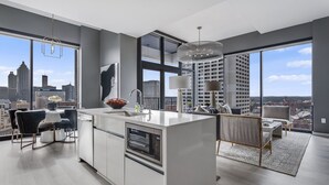 Una cucina moderna con una grande isola, un'area pranzo con tavolo e sedie, e vista sulla città attraverso ampie finestre.
