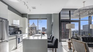 Una cucina moderna con isola centrale, elettrodomestici in acciaio inossidabile e vista sulla città attraverso ampie finestre.