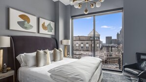 Una camera d'albergo moderna con un letto grande, vista sulla città e opere d'arte alle pareti.