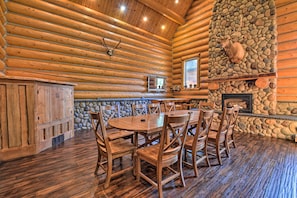 A log cabin interior with a stone fireplace, wooden dining table, and chairs. - Custom Bitterroot Valley Cabin w/ Hot Tub & Views! (Conner)